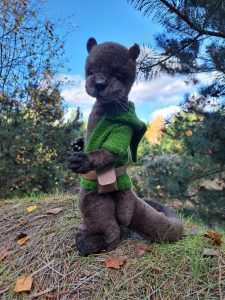 otter in a green jacket in the forest - teddy style toy